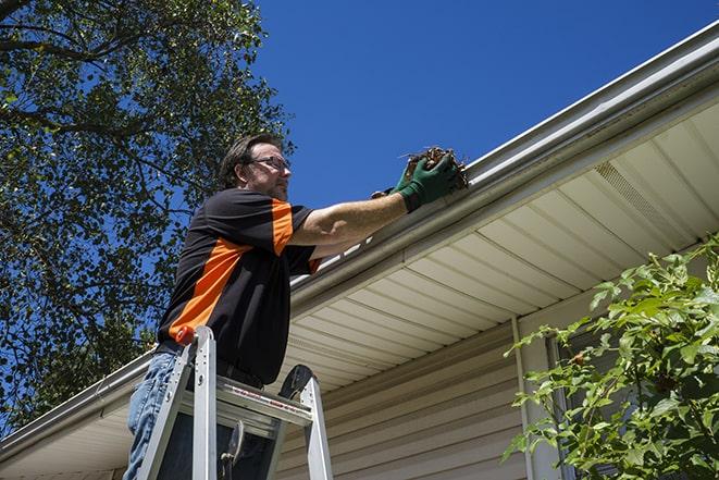 a homeowner repairing their gutter with tools in Camden